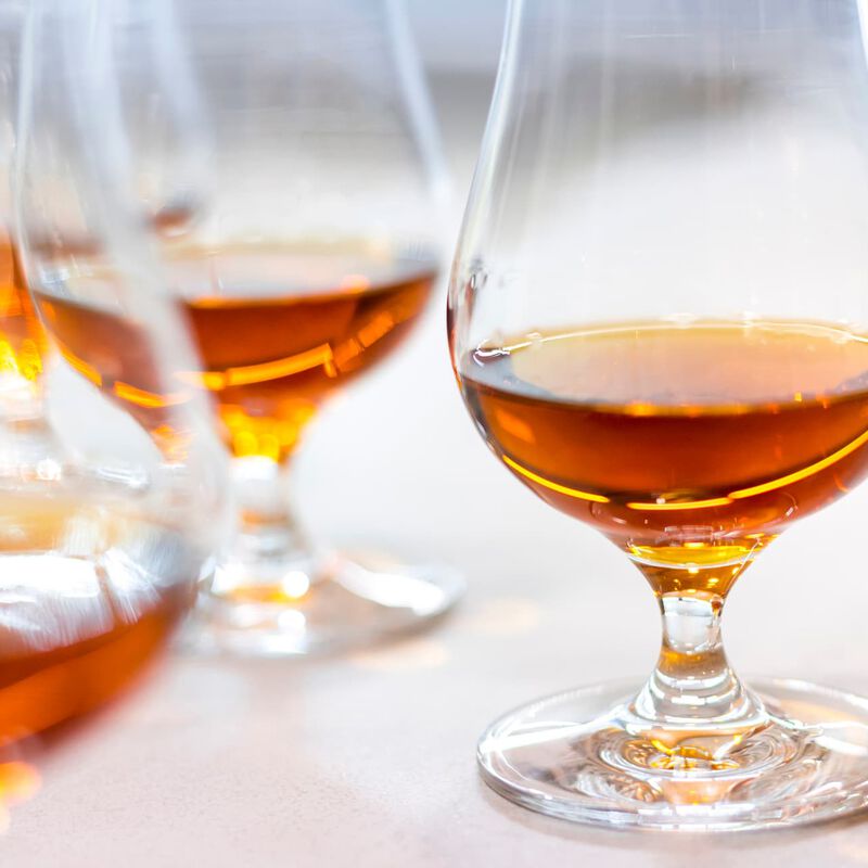Multiple tasting drams of whiskey are shown on a white tablecloth